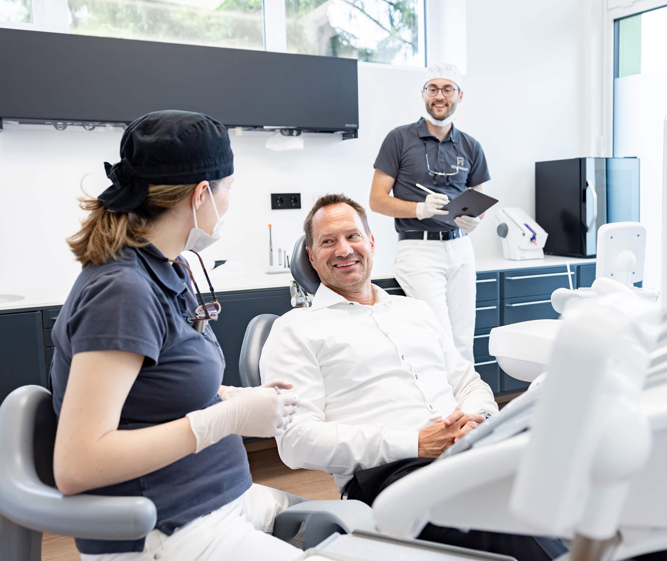 Patient im Gespräch mit dem Team am Behandlungsstuhl in der Ordination dentalReinisch